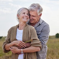 Couple smiling while hugging in field outside