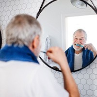 A senior man brushing his teeth in front of a mirror