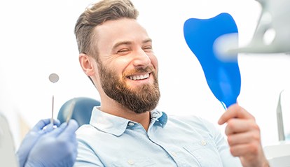 Man smiles into mirror after getting dental bonding in St. Albans 