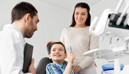 little boy with toothbrush in dental chair 