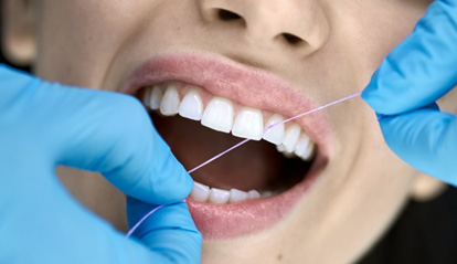 Dental hygienist flossing patient's teeth
