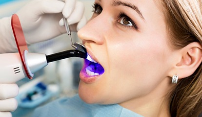 woman getting tooth-colored filling hardened with curing light 