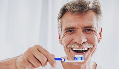 older man brushing his dental implants in St. Albans 