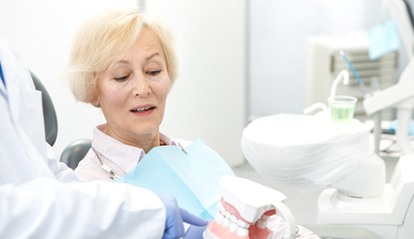 dentist showing dentures to an elderly patient