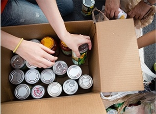 Person putting cans of food in cardboard box