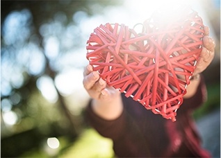 Person holding up heart shaped craft outdoors