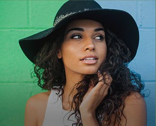 Woman wearing black hat in front of brick wall