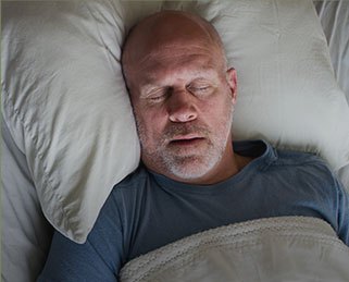 Older man sleeping soundly in bed