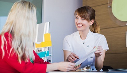 Woman reviewing dental insurance forms with a team member