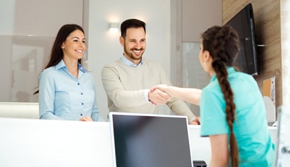 A couple shaking hands with the front desk receptionist