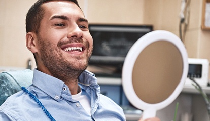 A young man looking at his smile in the mirror