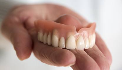 Hand holding a full denture