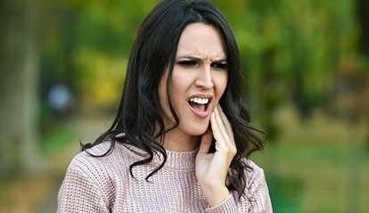 Woman holding cheek in pain