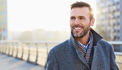 Man in jacket smiling and walking on bridge