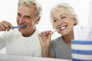 elderly couple brushing their teeth to prevent oral health problems 