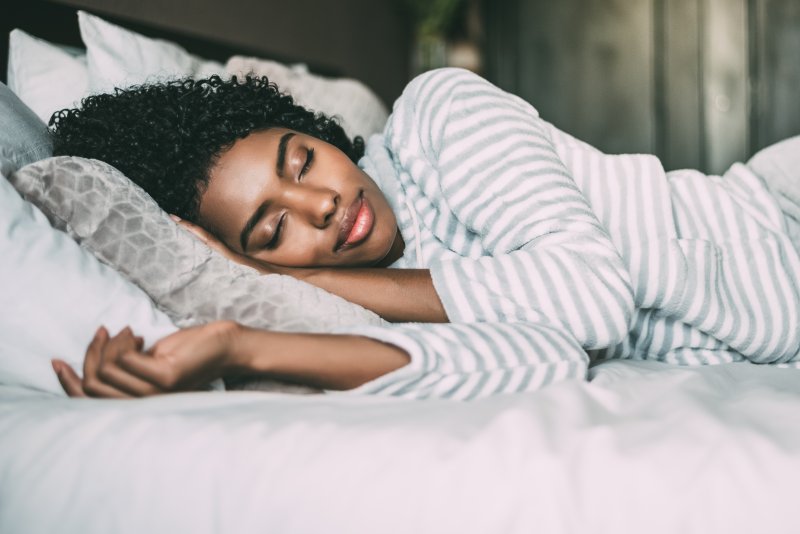 a woman lying on her side while in bed and asleep