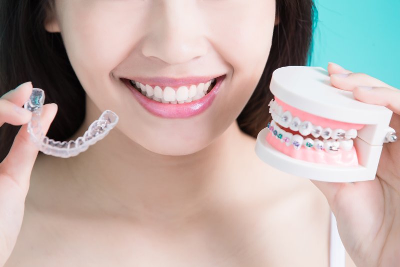 girl holding up Invisalign and braces