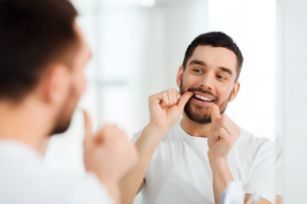 Man flossing his teeth in the mirror