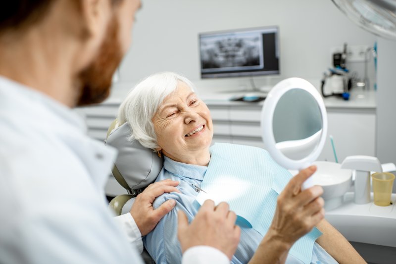 Happy elderly woman looking at her new dental implants.