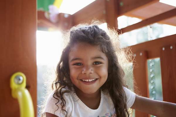 young girl smiling playing on play gym