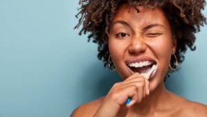 Head to shoulder view of a woman brushing her teeth and winking