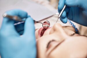 Closeup of woman having dental exam performed by dentist in blue gloves