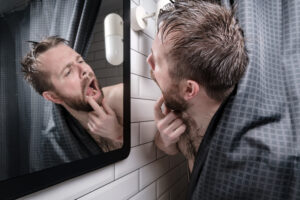 Man checking teeth in the mirror. 