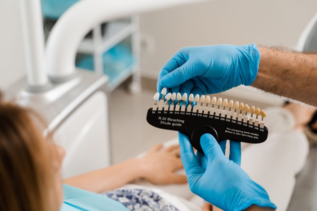 Dentist in blue gloves holding shade guide