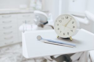 Clock on tray next to dental instruments in exam room